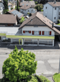 House: single family house, red brick, brown roof, glass windows, solar panels, garage, street with cars