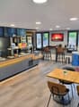 A modern restaurant with a wooden counter, black chairs, wooden tables, a fireplace, and a glass display case.
