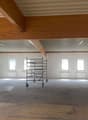 spacious room, wooden beams, white walls, metal roof, several windows, large steel scaffolding