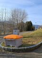residential area, roadside waste container, slope, greenery, clear sky