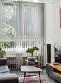 modern decor, brown sofa, coffee table, wall-mounted TV, wooden TV stand, floor lamps, decorative items, large window with vertical blinds