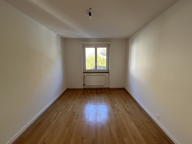 empty room, hardwood floors, white walls, large window, radiator, electrical outlet
