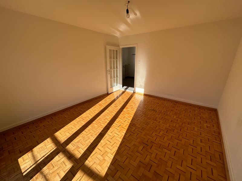 empty room, wooden floor, white walls, open door, light bulb hanging from ceiling