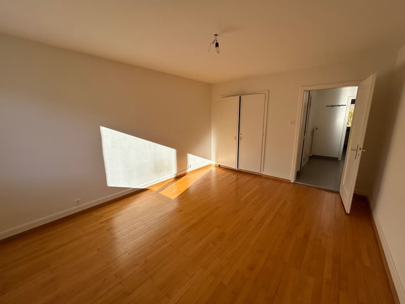 Empty room with white walls, wooden floor, three doors, one of which is open