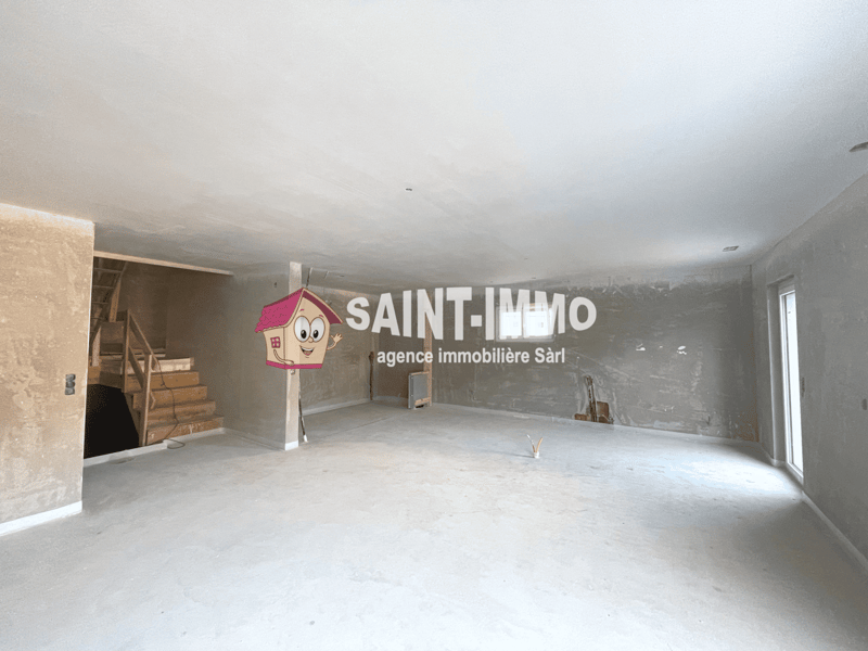 The image shows a large, open space with unfinished walls and floors. The space appears to be an office or commercial property, as indicated by the large 'SAINT-IMMO' logo on the wall, which is an agency immobilière (real estate agency) Sarl (limited liab