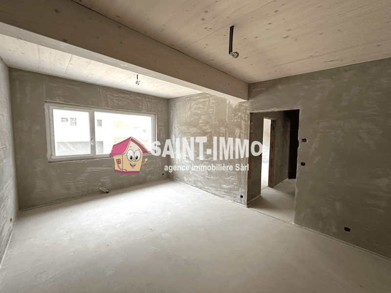 Unfinished room with concrete walls and ceiling, window, and Saint-Immo real estate agency logo on the wall.