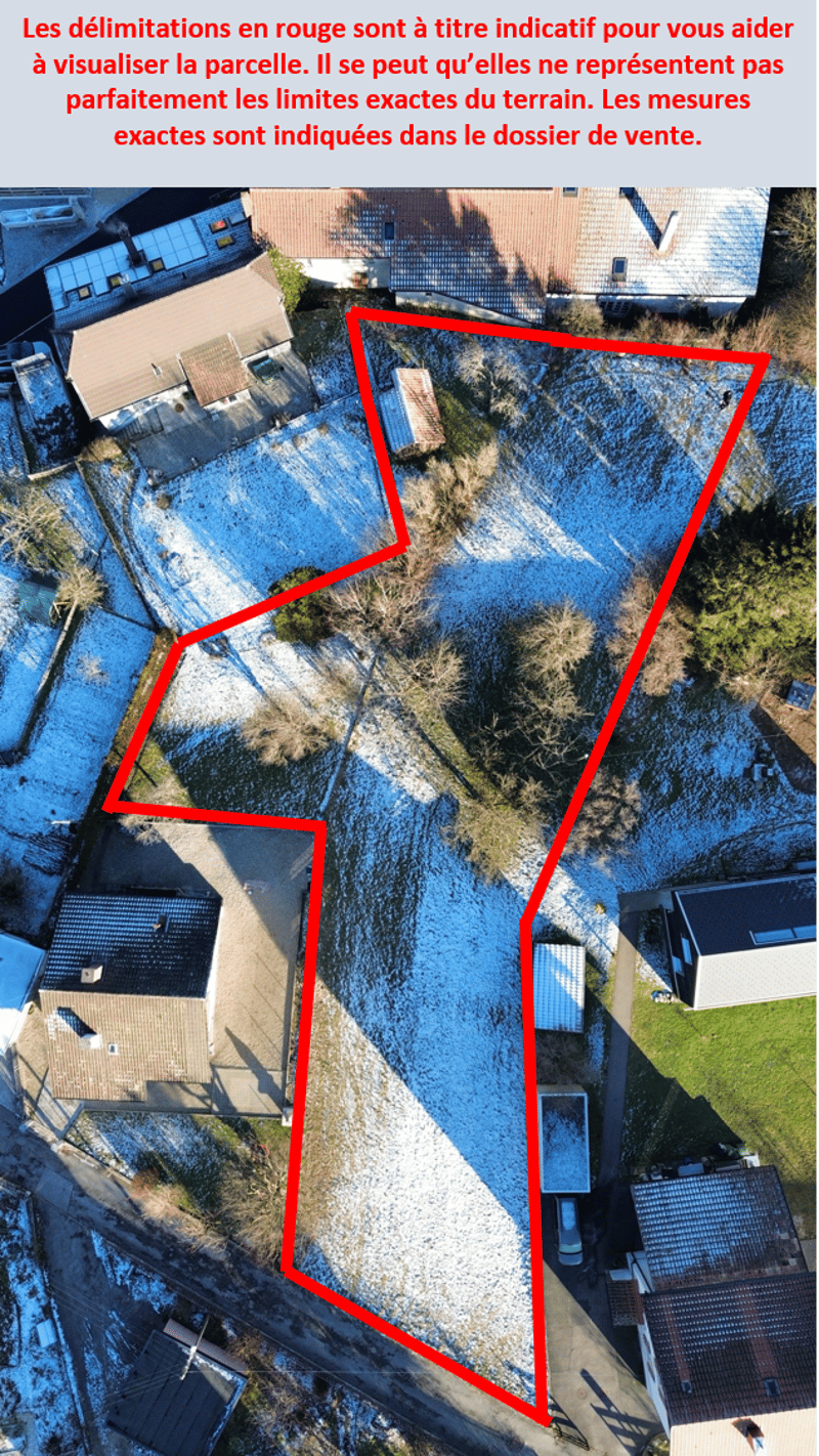 An aerial view of a residential area. The plot is demarcated by red lines. Several houses and buildings are visible in the image, with some having snow on their roofs.