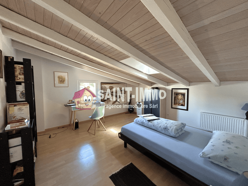 Room with wooden floor, white walls, a bed, chair, desk, bookshelf, picture frames, radiator
