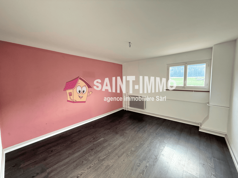 an empty room with wooden floors, pink wall with cartoon character and white radiator