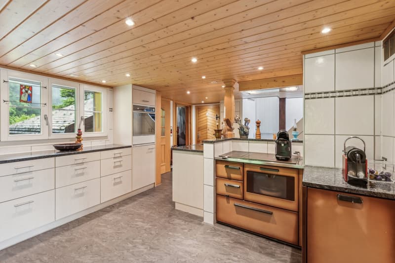 Spacious kitchen with wooden ceiling, white cabinets, granite countertops, stainless steel appliances including a dishwasher, and decorative accents