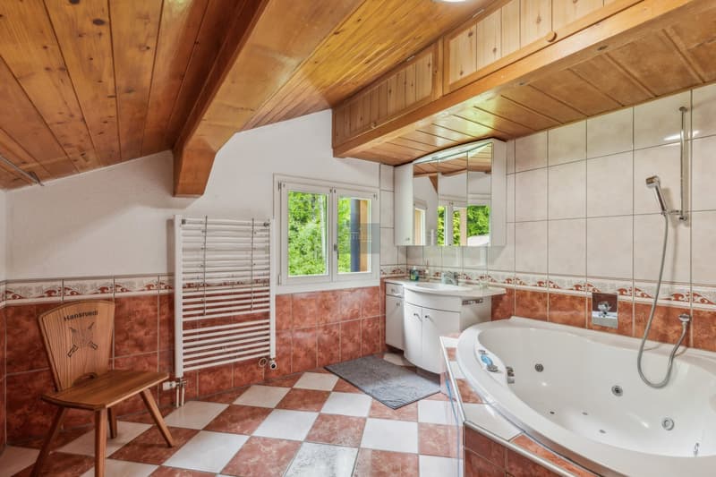 Spacious bathroom with wooden ceiling, tiled floor in a checkered pattern, a large bathtub, a vanity with a mirror, and a towel warmer.