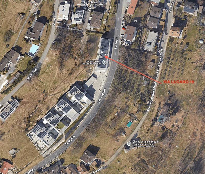 Aerial view of a residential area with multiple houses and buildings, a road, and a swimming pool.