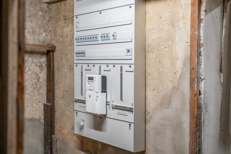 Electrical panel with various circuit breakers and a digital meter