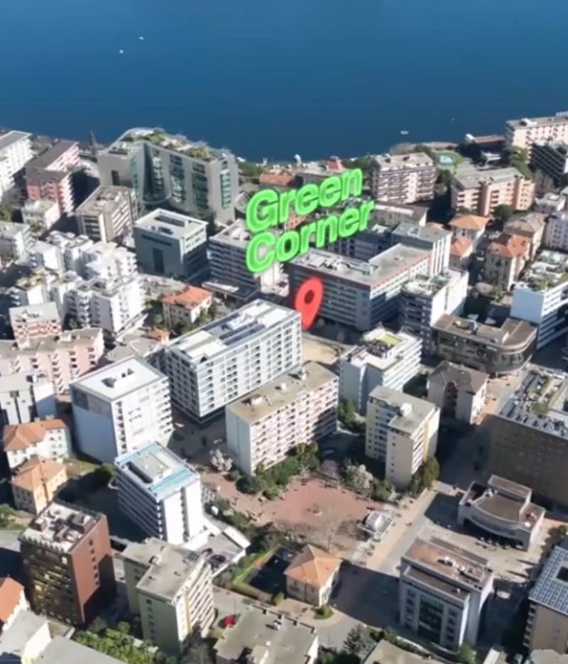 Aerial view of a densely populated urban area with high-rise buildings, including a large green sign that says 'Green Corner' visible in the center of the image.