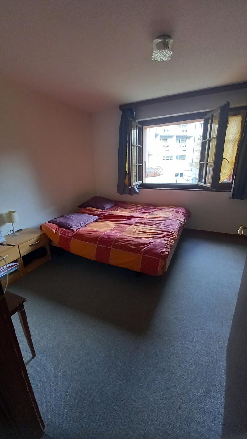 Bedroom with a double bed, nightstand, lamp, and a window with a view of the outside