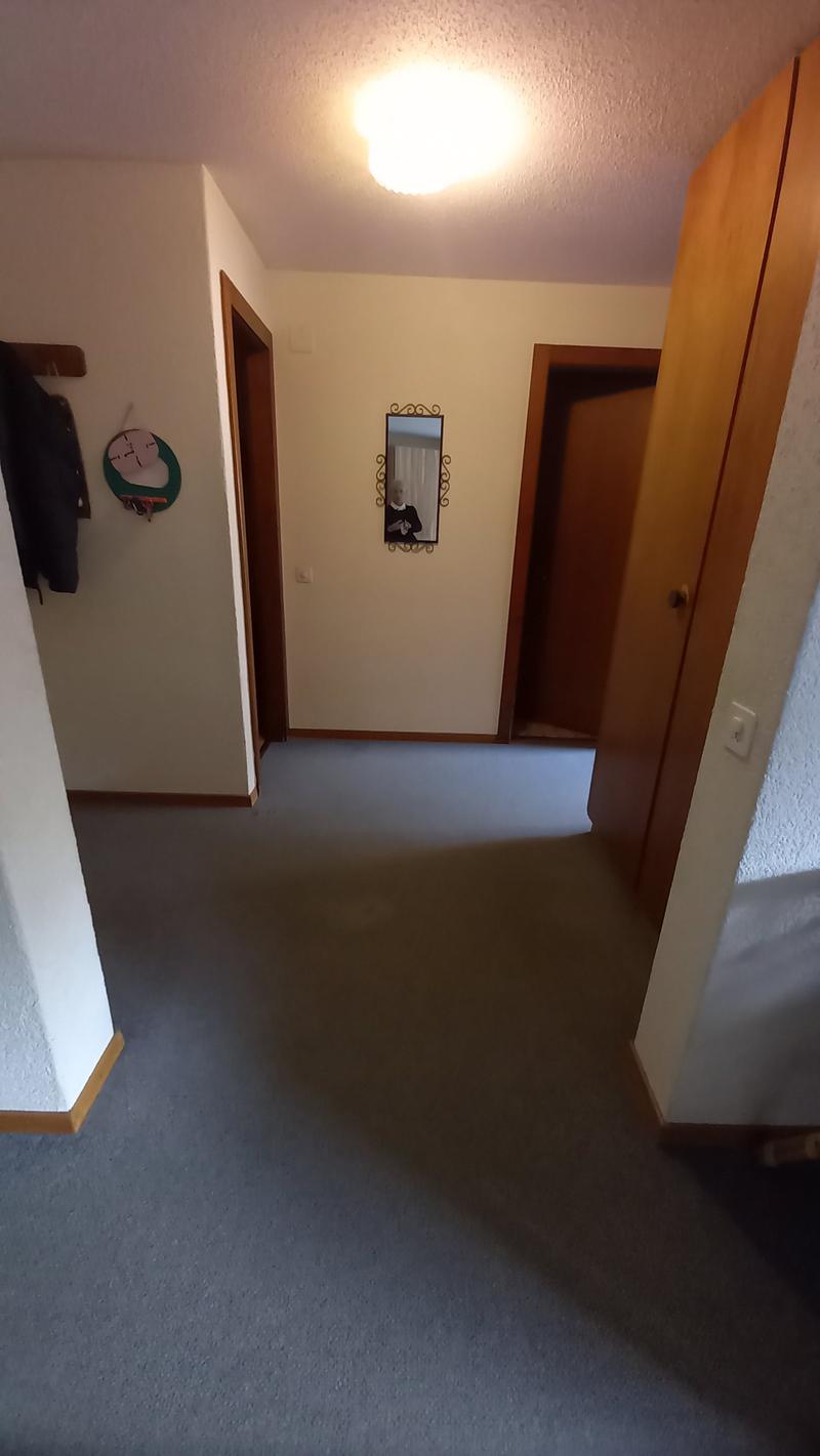 Empty room with carpeted floor, white walls, two doors, a mirror, and a light fixture on the ceiling.