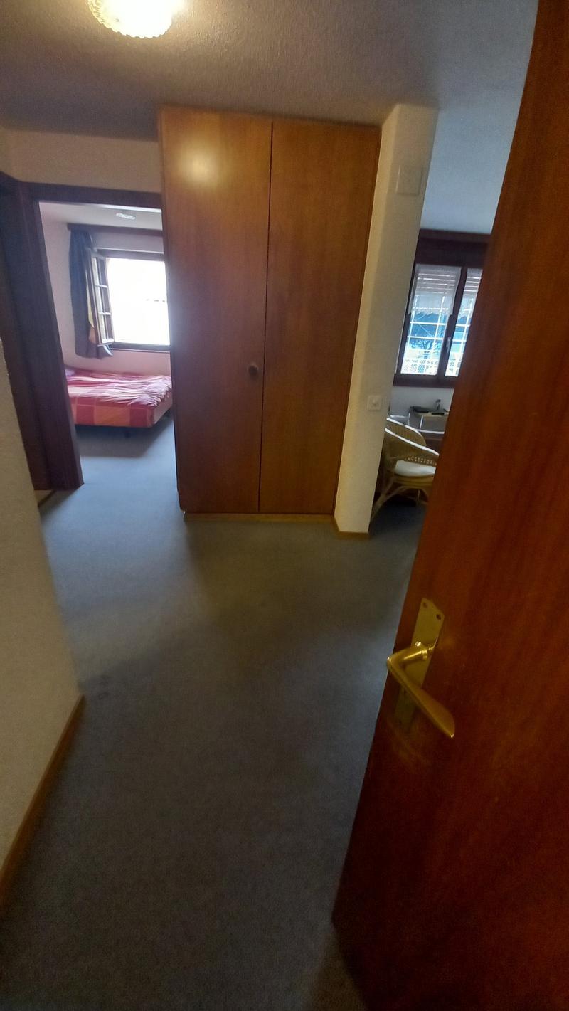 Empty room with carpeted floor, wooden wardrobe, bed, and windows