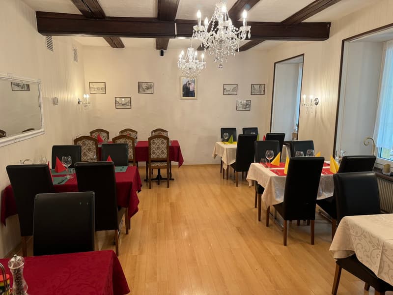 empty restaurant, wooden floor, dining tables, red tablecloths, chairs, chandeliers, picture frames on the wall, mirrors, and radiators
