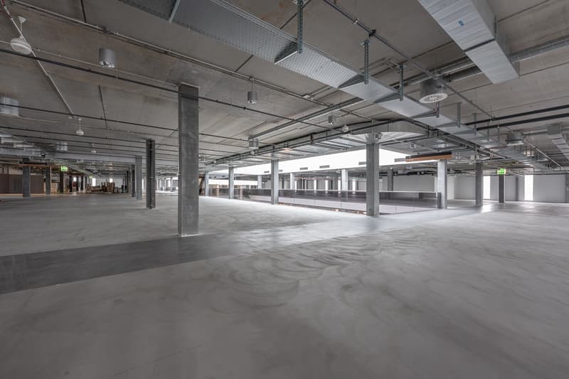 wide open space, concrete floor, exposed beams, and metal structures, with no furnishings
