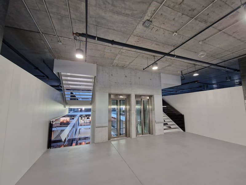 underground parking area, two elevators, white walls, steel stairs, modern lighting