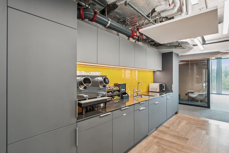 Grey cabinets, countertop, sink, faucet, coffee machine, microwave, yellow accent wall, window, flooring