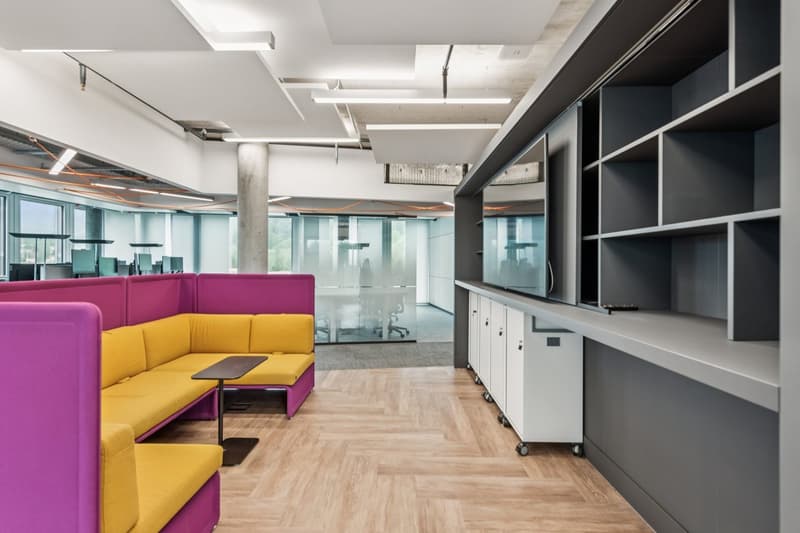 wooden floor, modular seating, glass walls, shelves, small desk, monitors