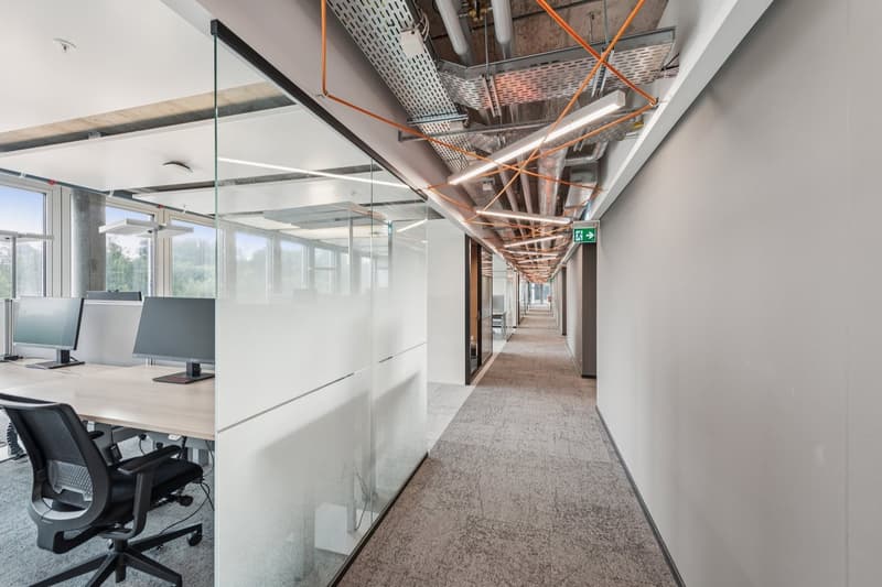 office corridor with office room, glass walls, desk, two monitors, swivel chair