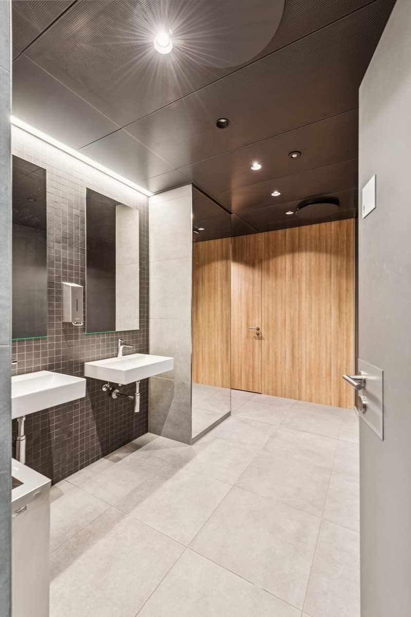 Bathroom with tiled floor, wooden walls, sinks, mirror and a soap dispenser