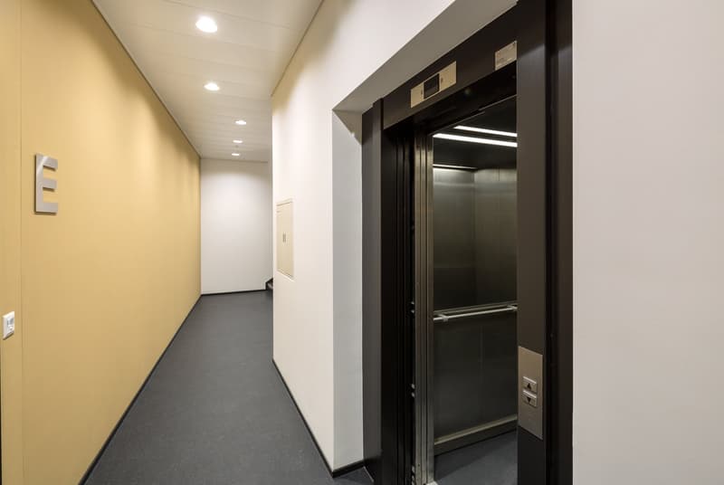 Empty hallway with elevator shaft and open elevator door.