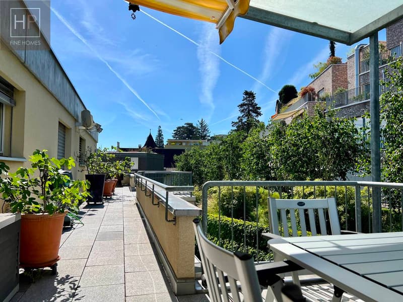 ein Balkon mit einem Tisch, Stühlen und Topfpflanzen auf der Terrasse / a balcony with a table, chairs and potted plants on the terrace