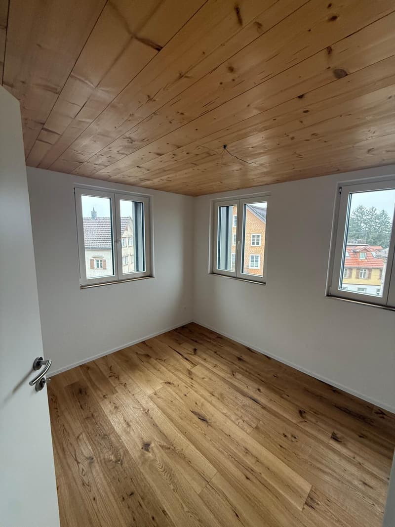 empty room with wooden flooring and white walls, three windows
