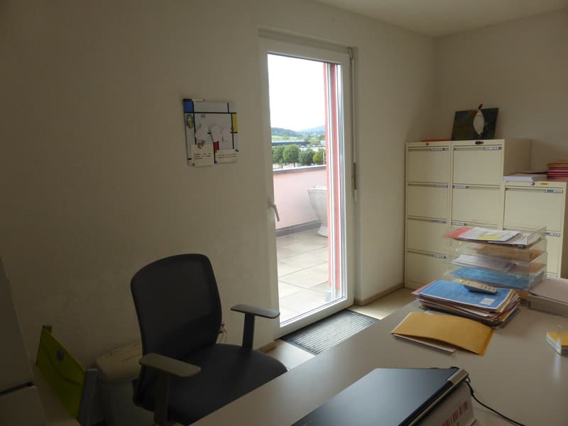 Office room with black chair, glass door, balcony, filing cabinets, desk, paperwork, laptop, papers