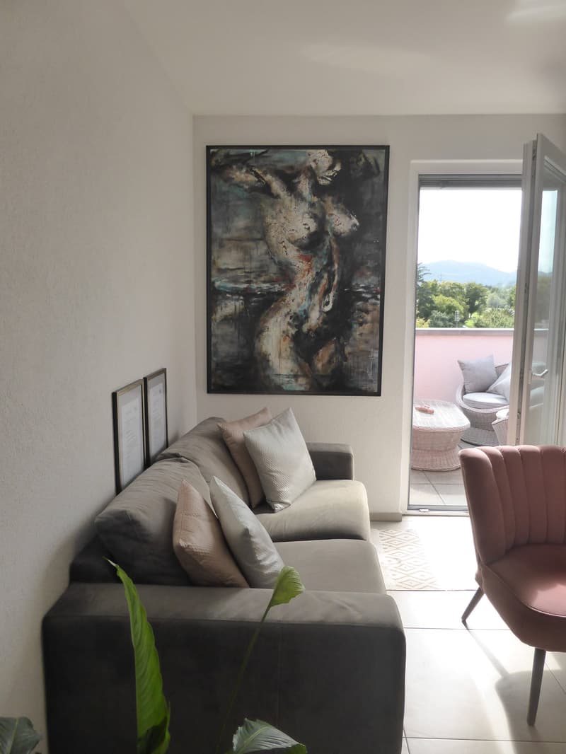 couch, coffee table, modern painting, chairs, balcony with table, decorative pillows, floor, trees and mountains in distance