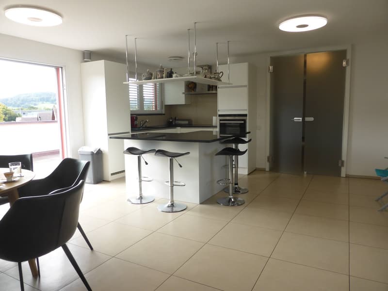 modern kitchen with black countertops, white cabinets, hanging lamps, open plan to living area, windows, balcony, large glass window