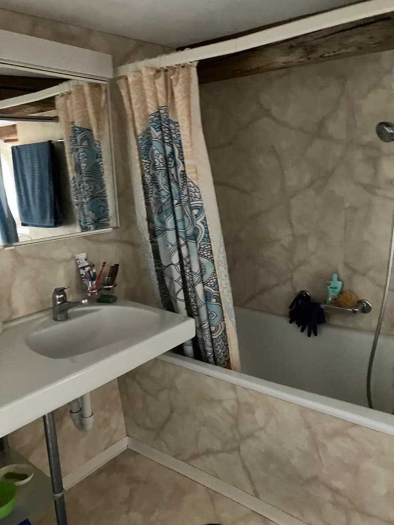 white sink, bathtub, mirror, shower, tiled wall, shelves, hanging items