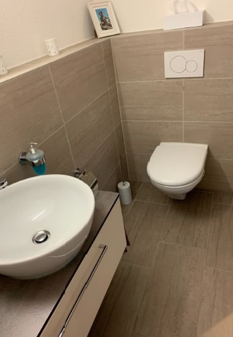 Bathroom with toilet, sink, tile flooring, wall mounted power outlet, tissue holder
