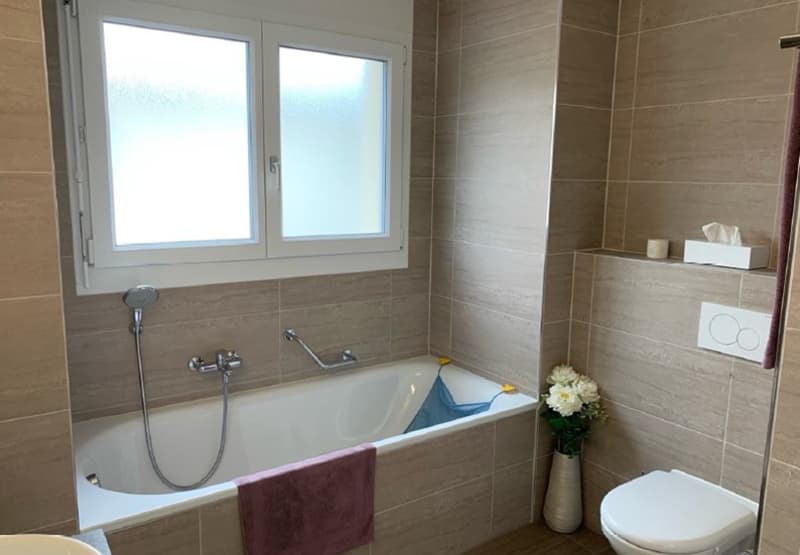 white bathtub, white toilet, white sink, window, beige tiles