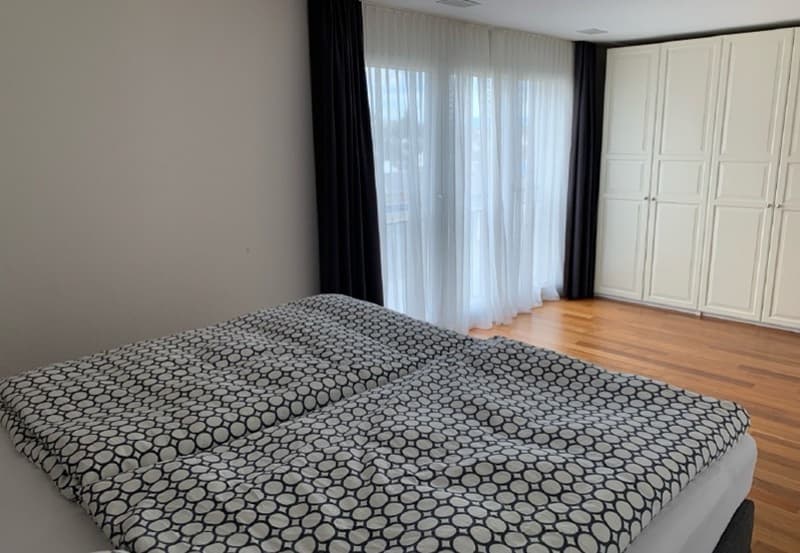 modern bedroom with wooden floor, large bed, large windows, built-in wardrobes