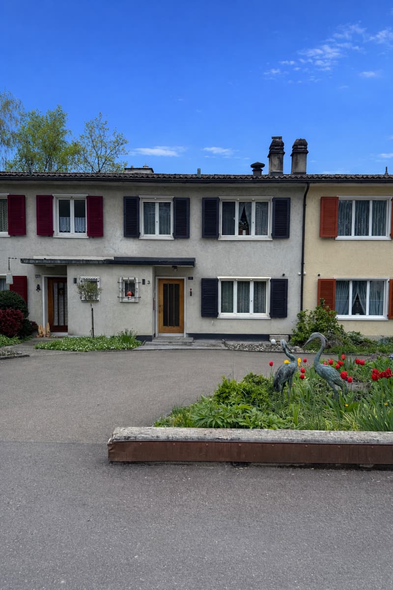 3 story house, red shutters, beige walls, 3 windows on each floor, 2 doors, garden with flowers and plants, 2 cranes statues
