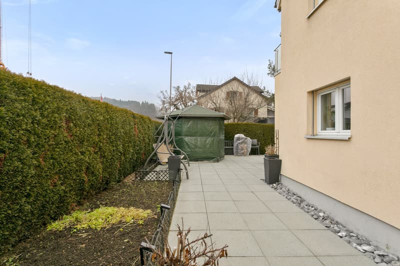 well-maintained, paved patio, potted plants, hedge, small greenhouse, bench, garden light, fenced