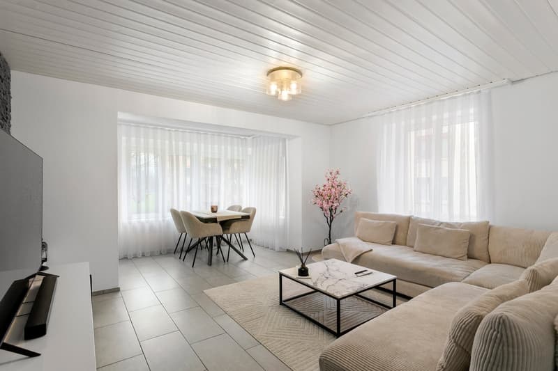 living room with dining area, couch, coffee table, floor lamp, TV, white curtains, tiled floor