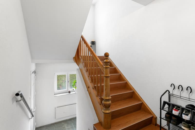 white walls, wooden stairs, shoe rack, radiator, candle, small plant