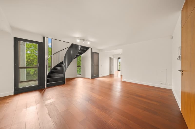 Open-plan living room with a wooden staircase leading to upper floors.