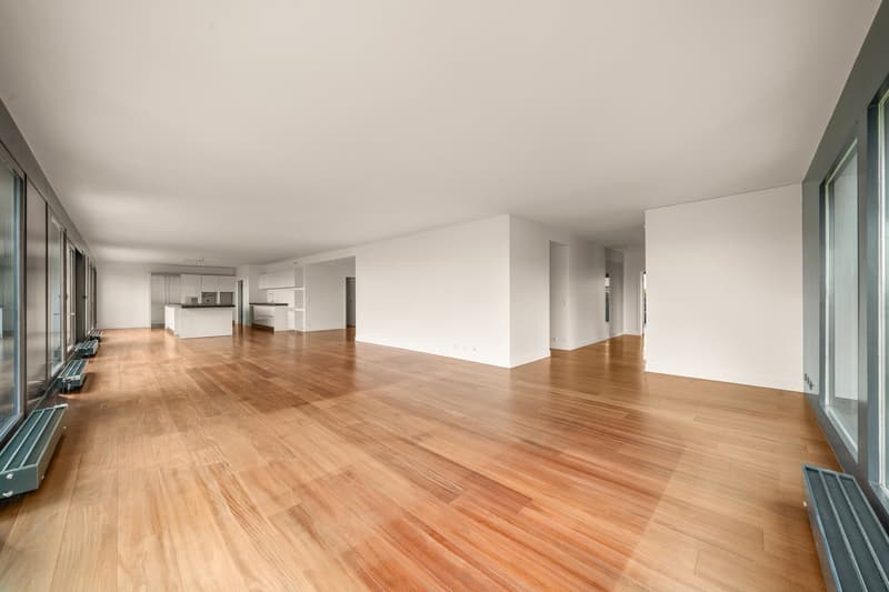 large open living space, wooden floors, tall windows, white walls, balconies on the sides