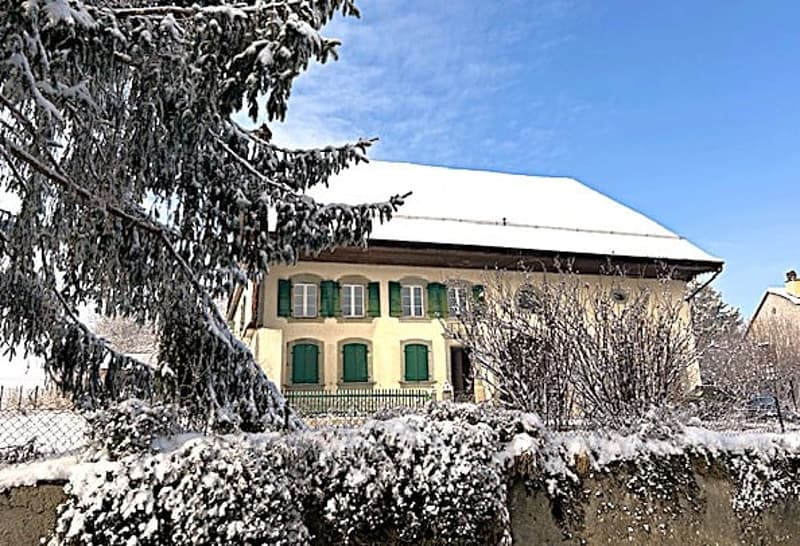 yellow facade, 12 windows, green shutters, gable roof, snow on roof