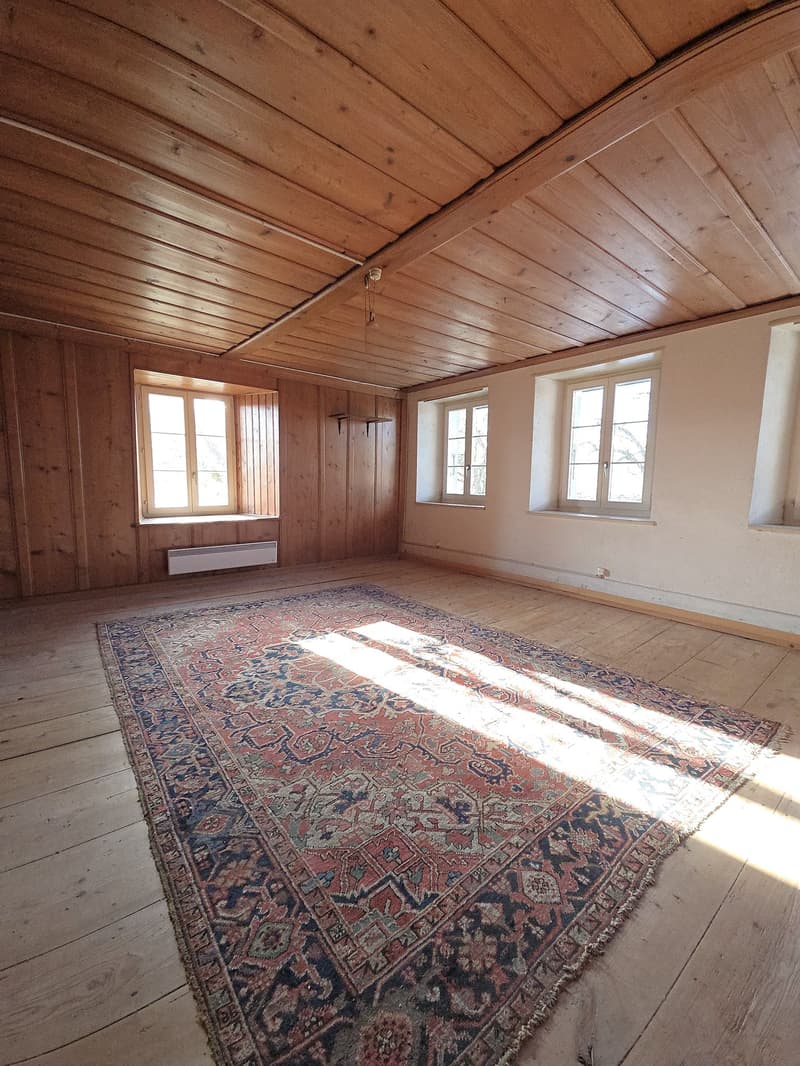 empty room, wooden floor, wooden walls, large carpet, three windows, heater