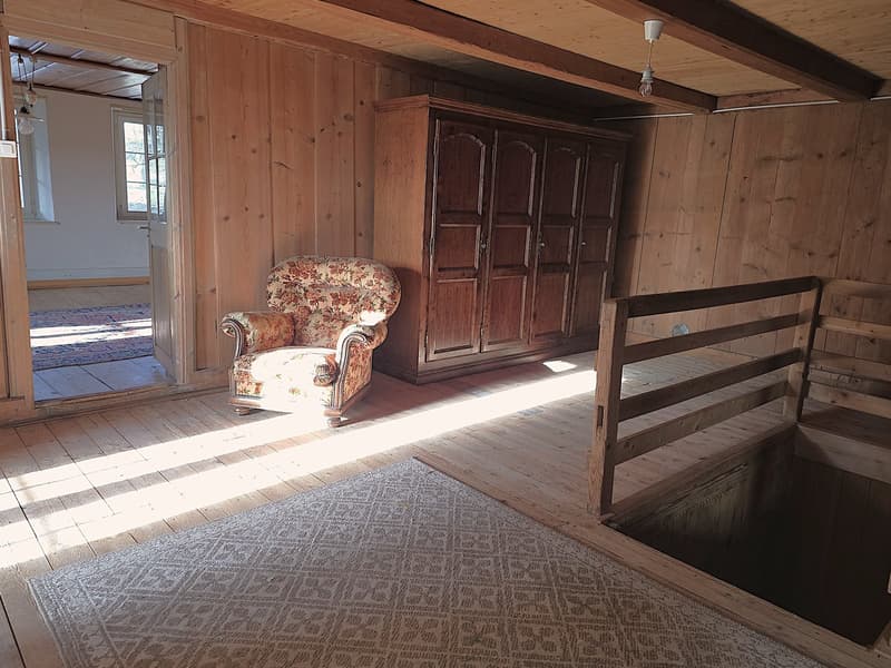 wooden walls, wooden floor, a large wooden wardrobe, a chair with a floral print, sunlight filtering through the window