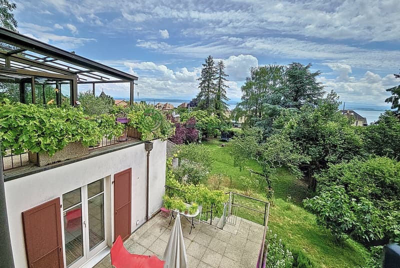 a house with a terrace, a covered terrace, a garden with various plants, trees, and a view of the surrounding landscape