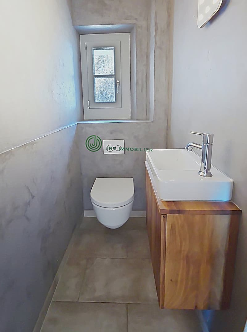 compact space with white toilet, white sink, wooden cabinet, tiled floor