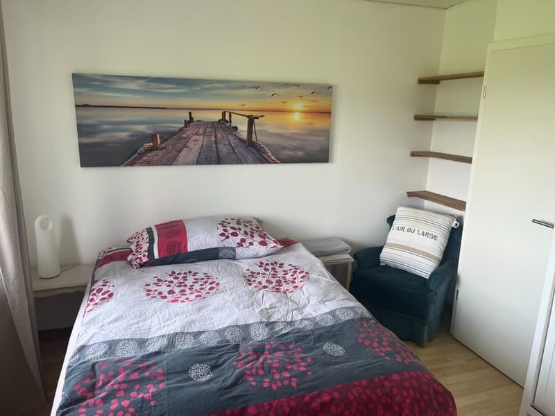 single bed, blue chair, wall-mounted shelf, bedspread, nightstand, painting, pillow